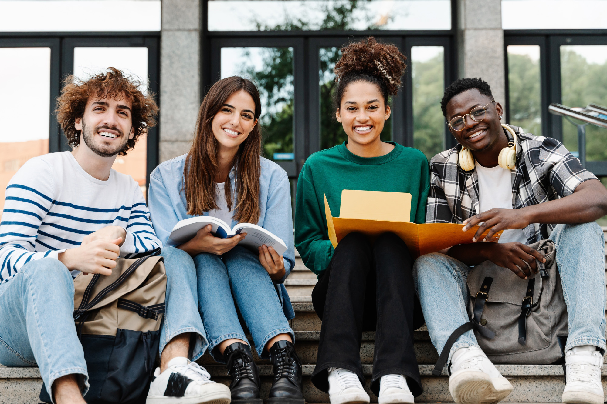 Four diverse students sitting on steps